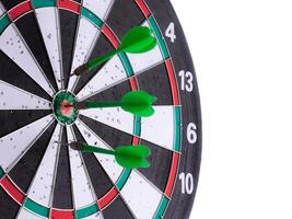 Side view of close up green darts hitting target on dartboard isolated on white background. Business success, precision, accuracy, focus, strategic planning, leadership, marketing concept. photo