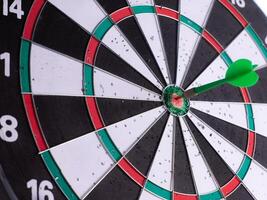 Close up of green dart hitting bullseye on dartboard with negative space. Business target, precision, focus, accuracy, success concept. Isolated goal achievement symbol. photo