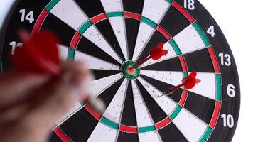 Close up hand holding red dart aiming at dartboard target. Business strategy, focus, precision, planning, leadership and success concept isolated on white background. photo