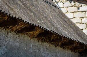 A roof with a wooden frame and a stone wall. The roof is slanted and has a pattern of wood photo