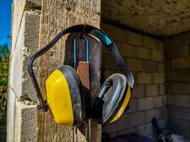 A pair of yellow and black earplugs are hanging on a wooden post. The earplugs are worn by someone who is trying to block out noise photo