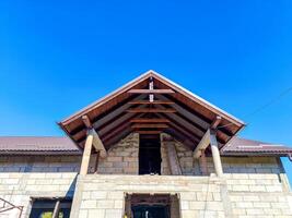 A house with a slanted roof and a large window. The roof is made of wood and the house is unfinished photo