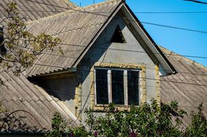 A house with a slanted roof and a window. The roof is made of shingles and the window is open photo