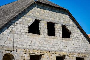 A building with a grey roof and a grey wall. The building has a lot of windows, but one of them is missing photo