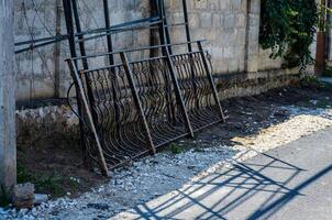 A fence is leaning against a wall. The fence is made of metal and has a lot of detail photo
