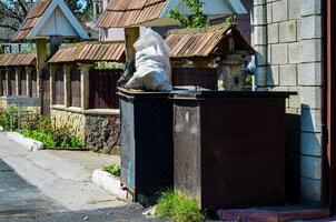 Two trash cans are next to each other, one of which is full of garbage. The other is empty photo