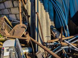 A pile of junk including a rusty chair and a metal grate. The pile is in a yard and he is a mess photo