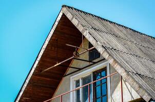 A house with a slanted roof and a window. The roof is made of wood and the window is made of glass photo
