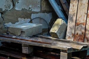 A pile of wood and bricks with a brick on top of a wooden pallet. The pallet is on the ground and the bricks are on top of it photo