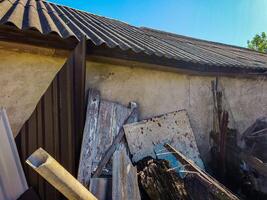 A pile of debris and junk is on the ground, with a roof above it. Scene is chaotic and disorganized photo