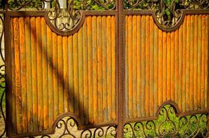 The fence is made of wood and has a rustic look. The wood is weathered and has a brownish hue. The fence is surrounded by a green grassy area photo