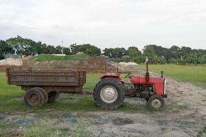 Red Tractor with Trailer on a Grassy Field photo