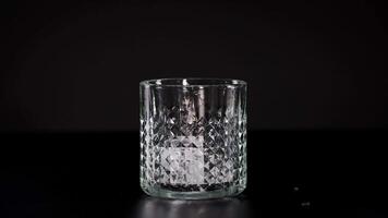 Ice cube splashes into an empty glass video