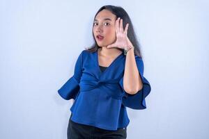 A young woman in a blue top posing with a surprised expression, holding her hand near her face playfully. photo