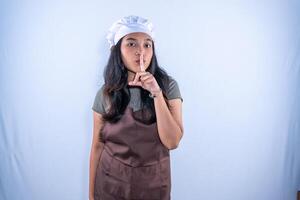 a woman in an apron is making a hush gesture photo