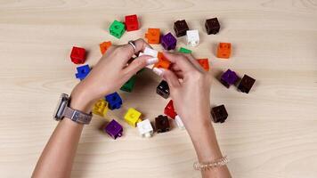 Hands assembling colorful linking cubes on a table video