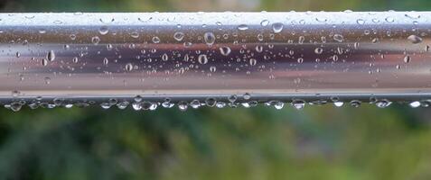 a close-up shot of a metal railing with water droplets clinging to it. photo