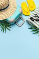 Suitcase, beach towel, flip flops, sunglasses and a straw hat suggesting summer vacation travel photo