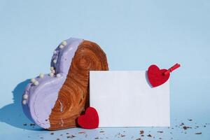 Empty paper note card template mock up Heart shaped blueberry flavor croissant on blue background with copy space. Puff pastry new trendy sweet dessert bakery. Creamy dough experiment photo