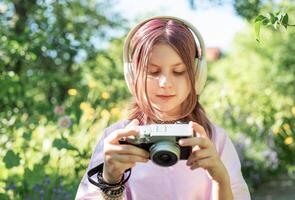 Young photographer taking pictures while listening music with headphones in a park during summer photo
