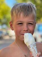 Boy on the beach eating ice cream in a waffle cone photo