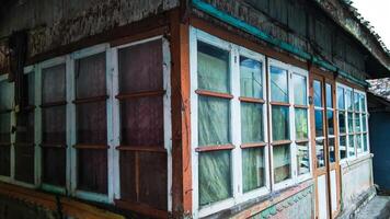 The corner of a simple Tengger tribe house is made of wood and is almost surrounded by glass windows. photo