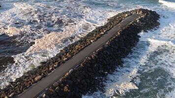 Aerial view of waves crashing against a rocky jetty at Brunswick Heads, NSW. Dynamic ocean scene with strong lighting and movement video