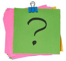 Stack of multicolored sticky notes with a black question mark drawn on the top green sticky note, secured with a blue paper clip. photo