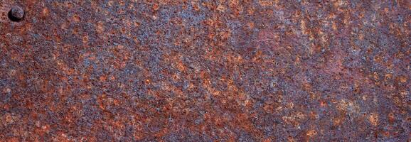 Close-up of heavily rusted metal with corroded, gritty surface texture and reddish-brown coloration photo