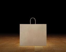 Large empty brown kraft paper bag isolated on wooden surface, black background. photo