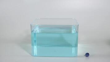 Sequential dropping of a marble into a water-filled container. video
