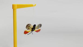 A butterfly model reacts to a magnet's force, illustrating attraction and repulsion in a controlled environment with neutral lighting video