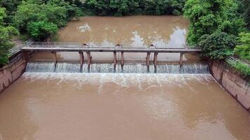 a dam releasing brown floodwater, irrigation, flood control, and environmental monitoring, Natural resource management and infrastructure, a dam discharging muddy floodwater with strong current video
