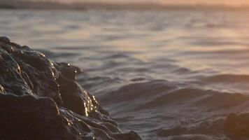 Beach rock against wave and sunset, slow motion video