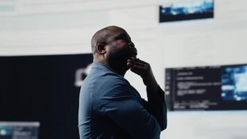 Preto programador especialista noivando dentro Programas desenvolvimento às uma Alto tecnologia área de trabalho, focado em grande dados painel. exibindo codificação vida e isto algoritmos dentro a tecnologia mundo. Câmera b. video
