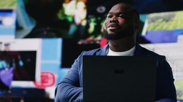 afrikansk amerikan specialist engagerande med media instrumentpaneler skärmar, understryker nätverkande med ai och teknologi. tech drivs kille ställer ut uppkopplad plattformar och internet kommunikation. kamera b. video