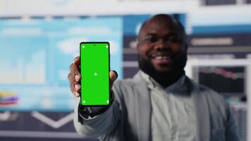 African american administrator uses copy space on phone and examines dashboards, ensuring analytics and performance metrics with KPI projections. Management decision for innovation. Camera B. video