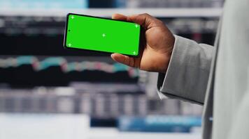 African american business leader uses green screen next to KPI metrics, ensuring company success development for a high end life. Young entrepreneur reviews fintech projections. Camera B. video