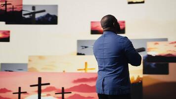 Spiritual believer meditates on faith and holiness in a pose of worship and surrender, praise the Lord. Background of crosses showcases religion and the higher power of devotion. Camera A. video