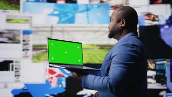 Professional content creator in a multitasking space holds green screen, leveraging social media, internet big data and cloud systems. Engaging followers to boost digital presence. Camera A. video
