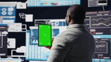 African american leader reviewing mockup screen with data insight for business development, surrounded by fintech charts and KPI projections. Financial performance and decision making. Camera A. video