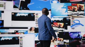 African American professional browses high tech environment with app icons, infographics and social networking feeds. Showcases big data on social media platforms, digital influence. Camera A. video
