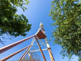 Old rusty red and white TV tower in Tbilisi against the background of blue sky photo