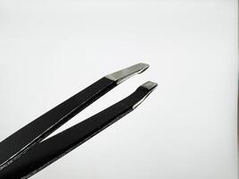 Black metal tweezers with a silver tip on a white background are on the left in the image photo