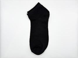 Black short men's socks on a white background one pair lie in the center of the image vertically and turned to the left from the center top view photo