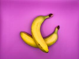 Two bright yellow bananas lying on top of each other, top view, center of image photo
