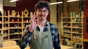 Caucasian man portrait smiling guy sculptor potter craftsman in pottery workshop designer artisan male small business owner craft shop art studio master handmade ceramics posing artist okay gesture video