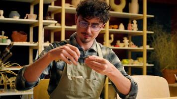 Male sculptor craftsman potter man Caucasian guy in pottery workshop art designer architect artisan holding measuring tool instrument ceramics design craft handmade drawing measure equipment working video
