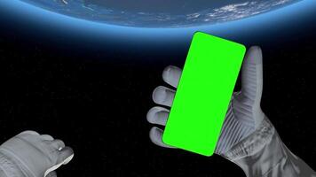 Astronaut in outer space holds a smartphone with green screen video