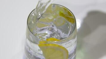 Lemon water glass slice of lemon on a glass of water and ice standing on a white table on the background of a decanter of water and two lemons. Beautiful still life of soft drinks video